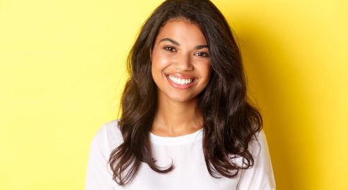 Close-up of attractive african-american woman, smiling and looking happy, standing over yellow background Close-up of attractive african-american woman, smiling and looking happy, standing over yellow background.