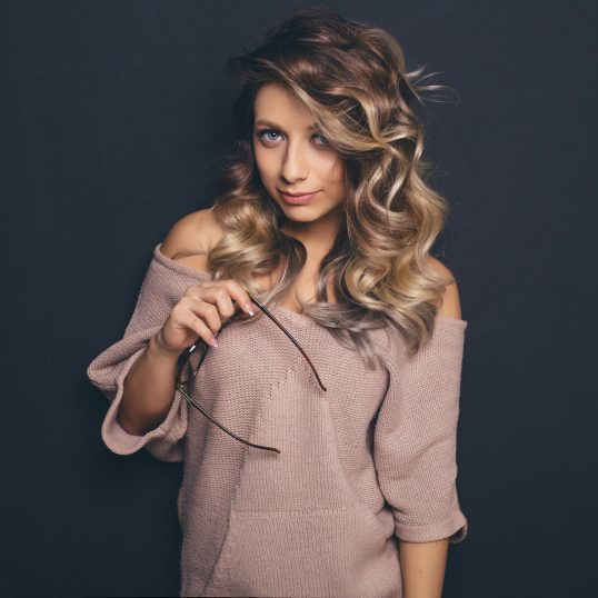 Portrait of a young beautiful blond-haired wearing trendy glasse Portrait of a young beautiful blond-haired wearing trendy glasses and casual clothes and posing over black background. Studio shot